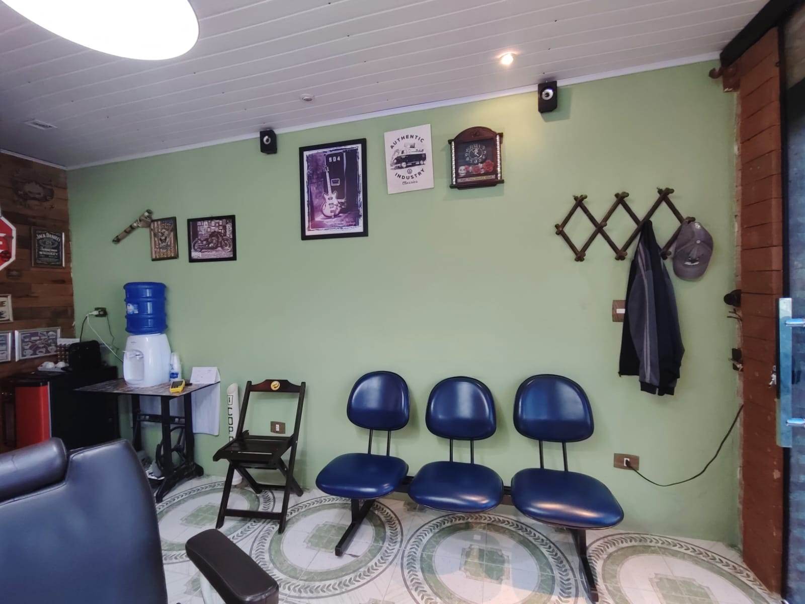 Sala de espera com cadeiras azuis e quadros de motos e guitarra