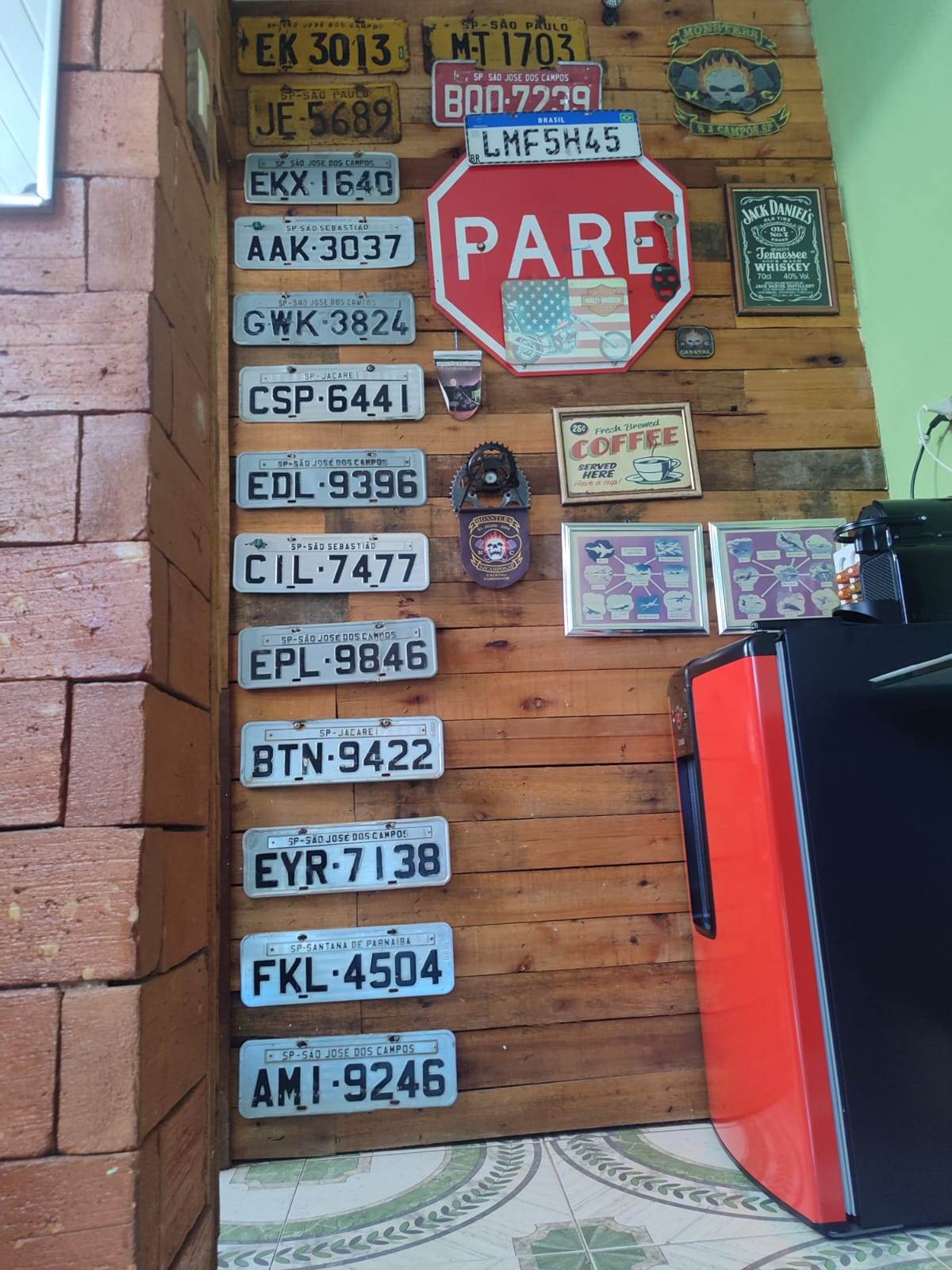 Parede de madeira com placas antigas de carro e uma placa de PARE