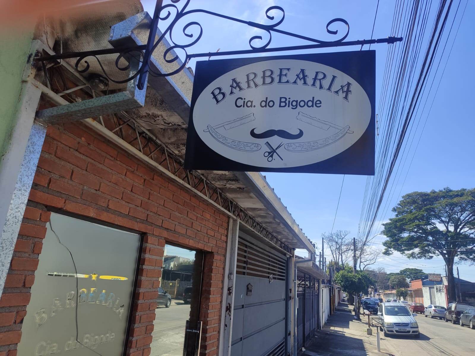 Letreiro pendurado da barbearia em suporte de ferro trabalhado